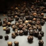 parfum fort en été — poivre et flacon en lumière sombre — Noble Essence