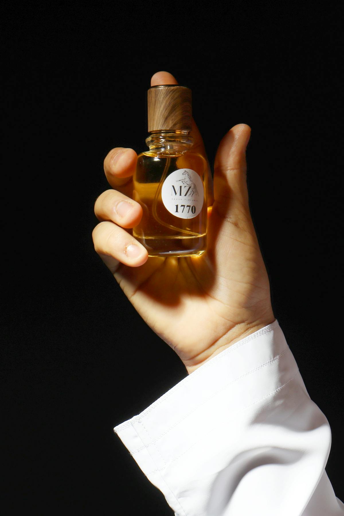 main tenant un flacon de parfum de niche élégant fond sombre — tester un parfum de niche avant d'acheter