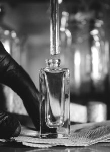 parfumeur dosant un liquide ambré à la pipette dans un atelier, étape de création d'un parfum