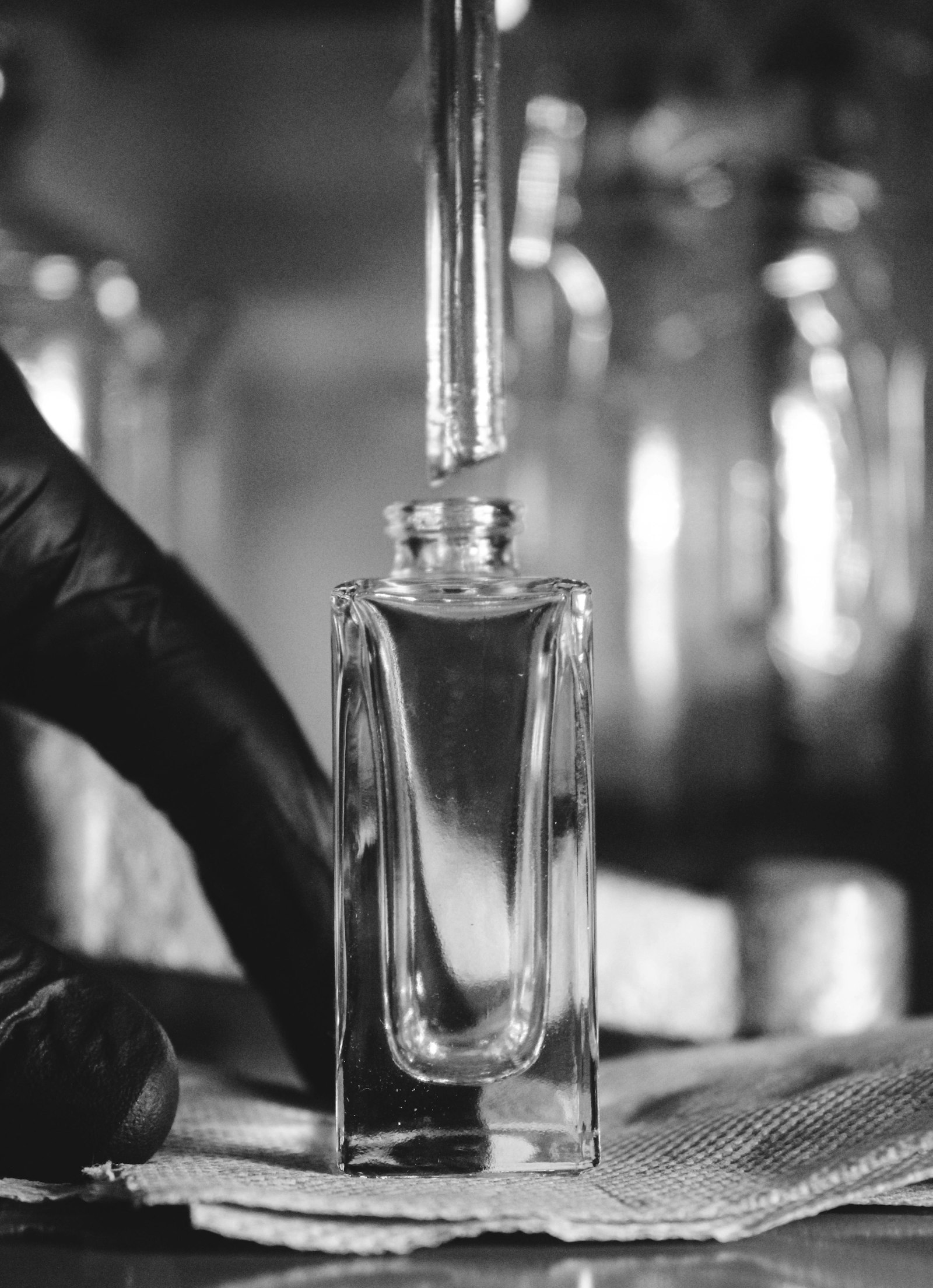 parfumeur dosant un liquide ambré à la pipette dans un atelier, étape de création d'un parfum