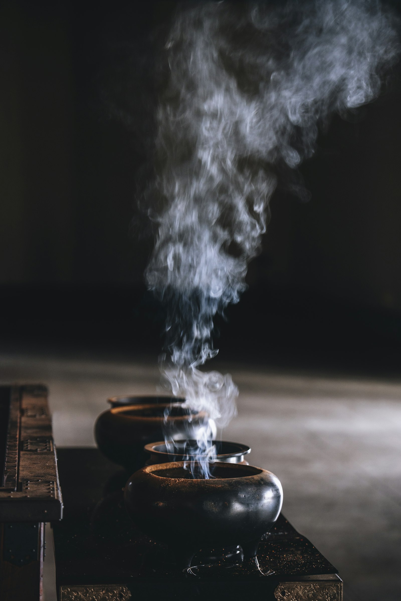 fumée de trois brûle-encens s'élevant en rangée, usage rituel de l'encens à travers les civilisations