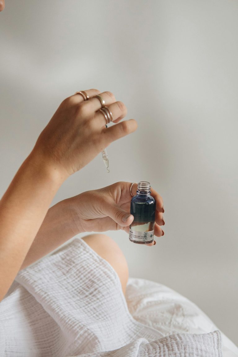 main tenant un flacon de parfum noir, geste associé à l'identité olfactive personnelle