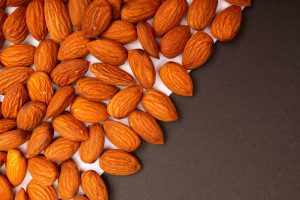 amandes brutes sur fond sombre, fruit à coque à l'origine de la note amande en parfumerie