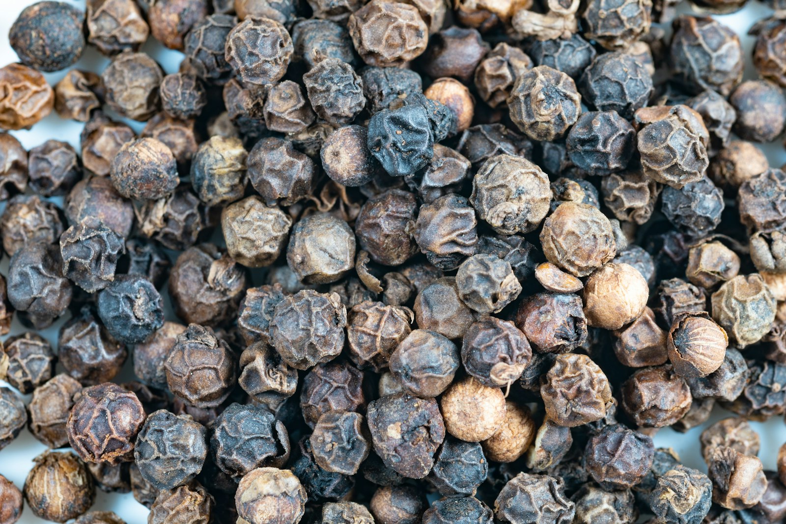 grains de poivre noir en gros plan, épice de tête utilisée en parfumerie
