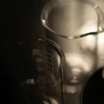 Plusieurs béchers en verre sur fond sombre — alcool et formulation en parfumerie — Noble Essence