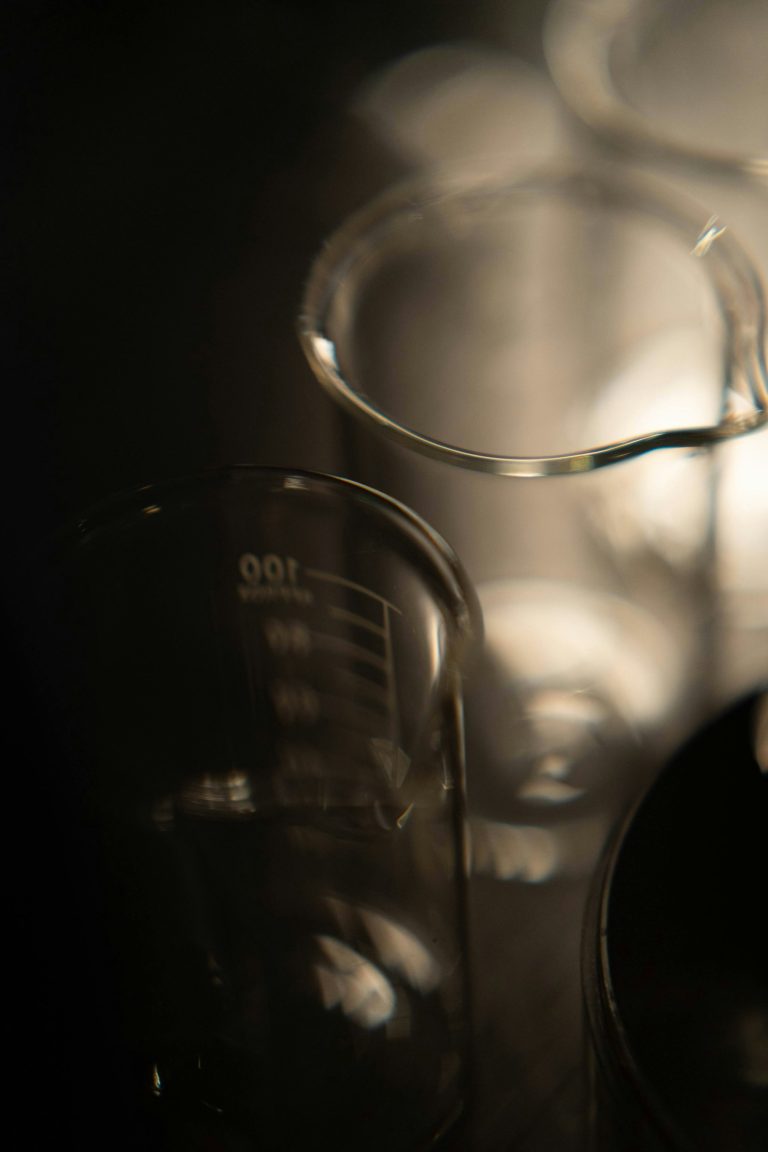 Plusieurs béchers en verre sur fond sombre — alcool et formulation en parfumerie — Noble Essence