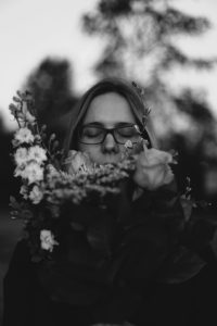 Photo en noir et blanc d'une personne sentant une fleur — anosmie et perception olfactive — Noble Essence