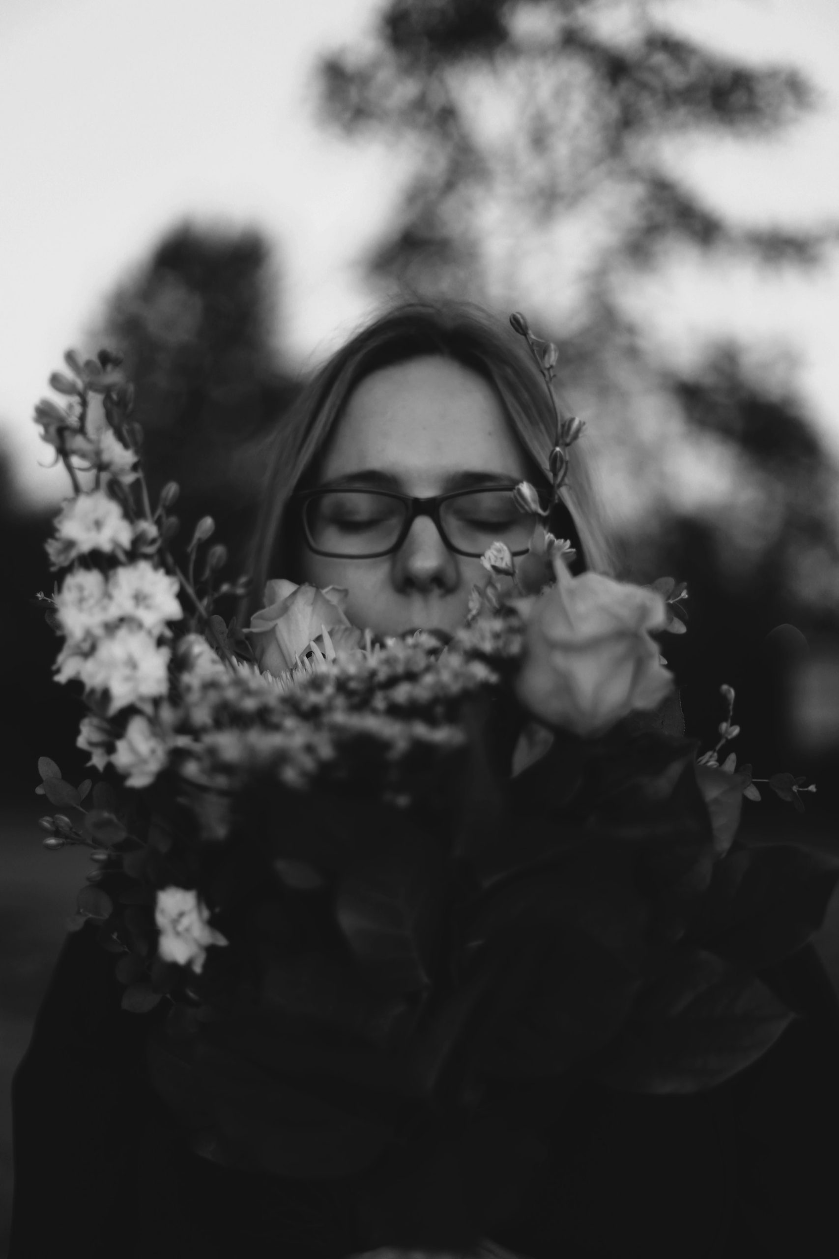 Photo en noir et blanc d'une personne sentant une fleur — anosmie et perception olfactive — Noble Essence