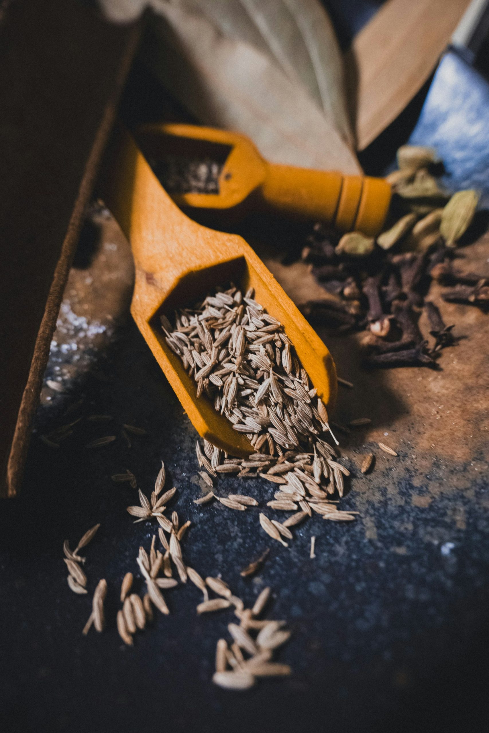 Cuillères en bois remplies de graines de cumin et d'épices — dosage précis en parfumerie — Noble Essence