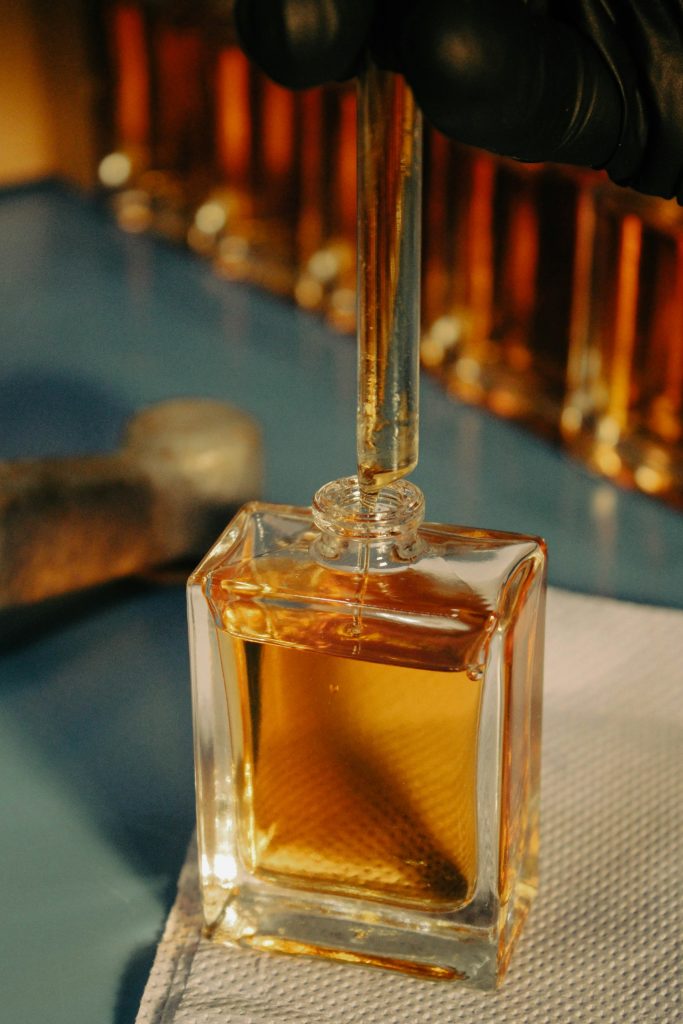 Main gantée de parfumeur manipulant un flacon en laboratoire — métier de nez — Noble Essence