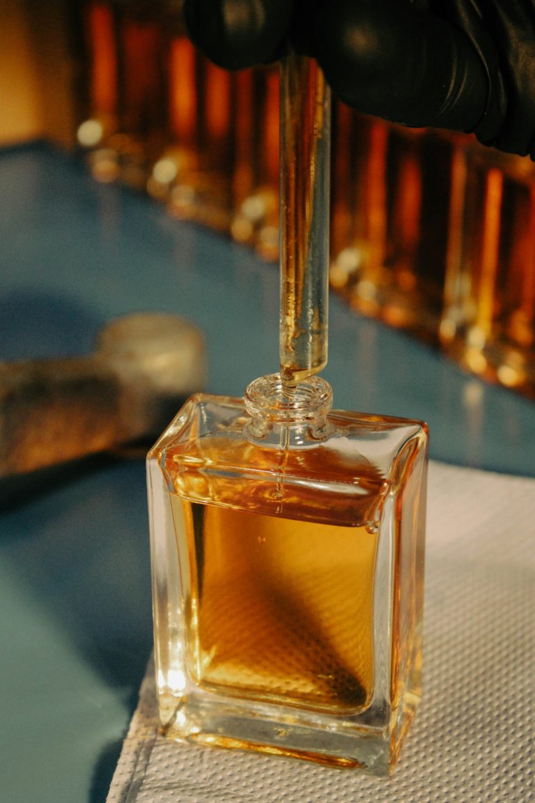 Main gantée de parfumeur manipulant un flacon en laboratoire — métier de nez — Noble Essence
