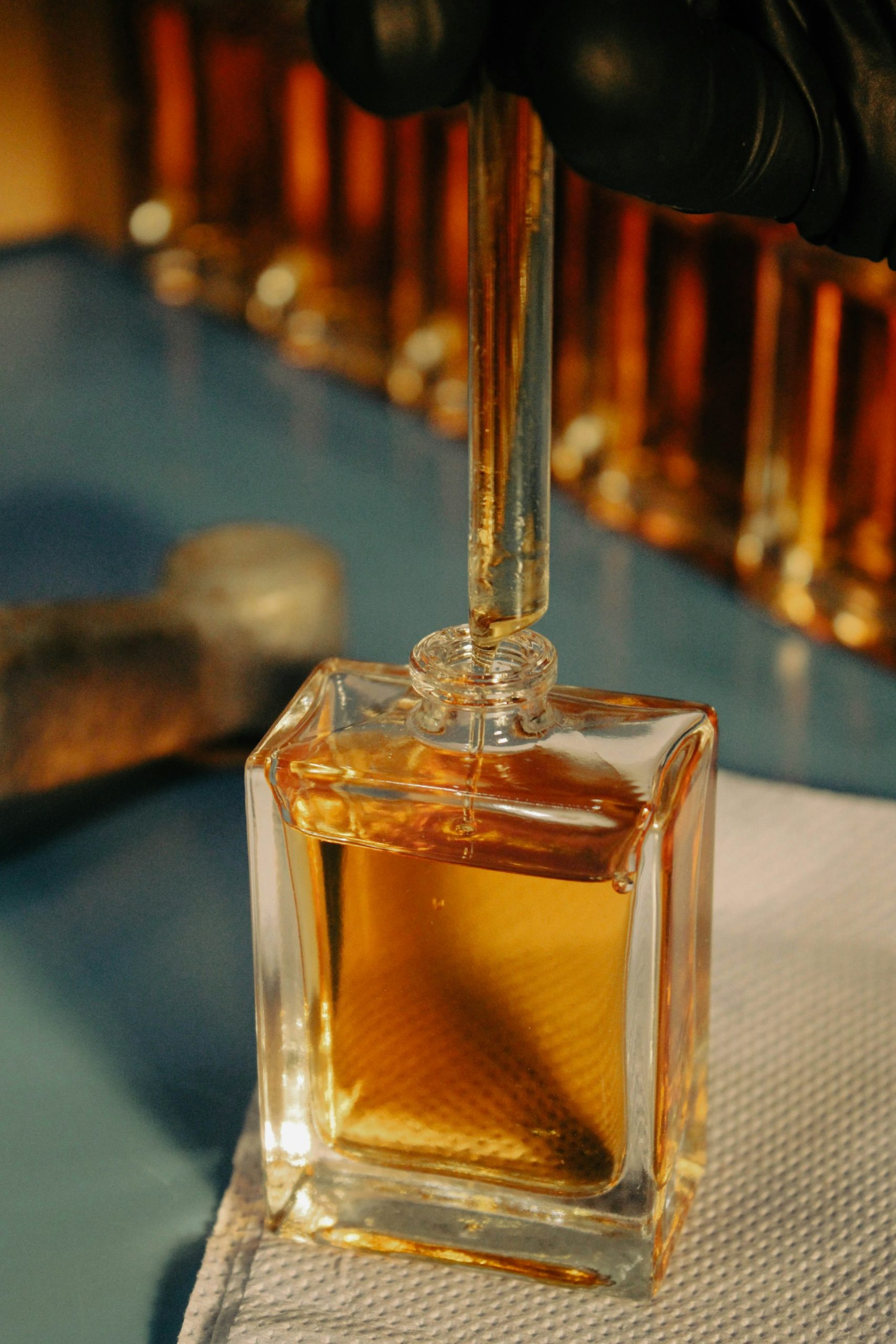 Main gantée de parfumeur en laboratoire, manipulant des matières de synthèse — Noble Essence