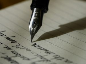 Stylo plume sur papier ligné noir — processus de création du nom d'un parfum — Noble Essence