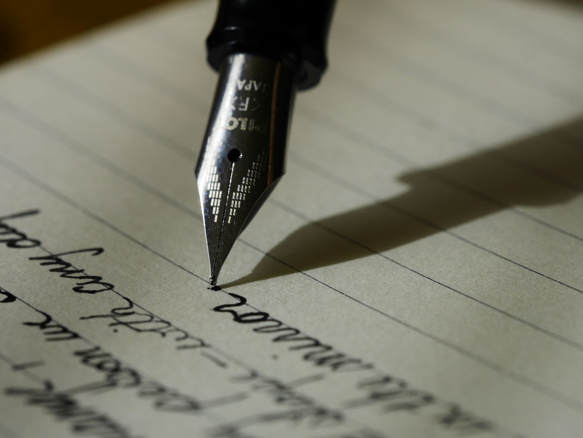 Stylo plume sur papier ligné noir — tenir un carnet olfactif — Noble Essence