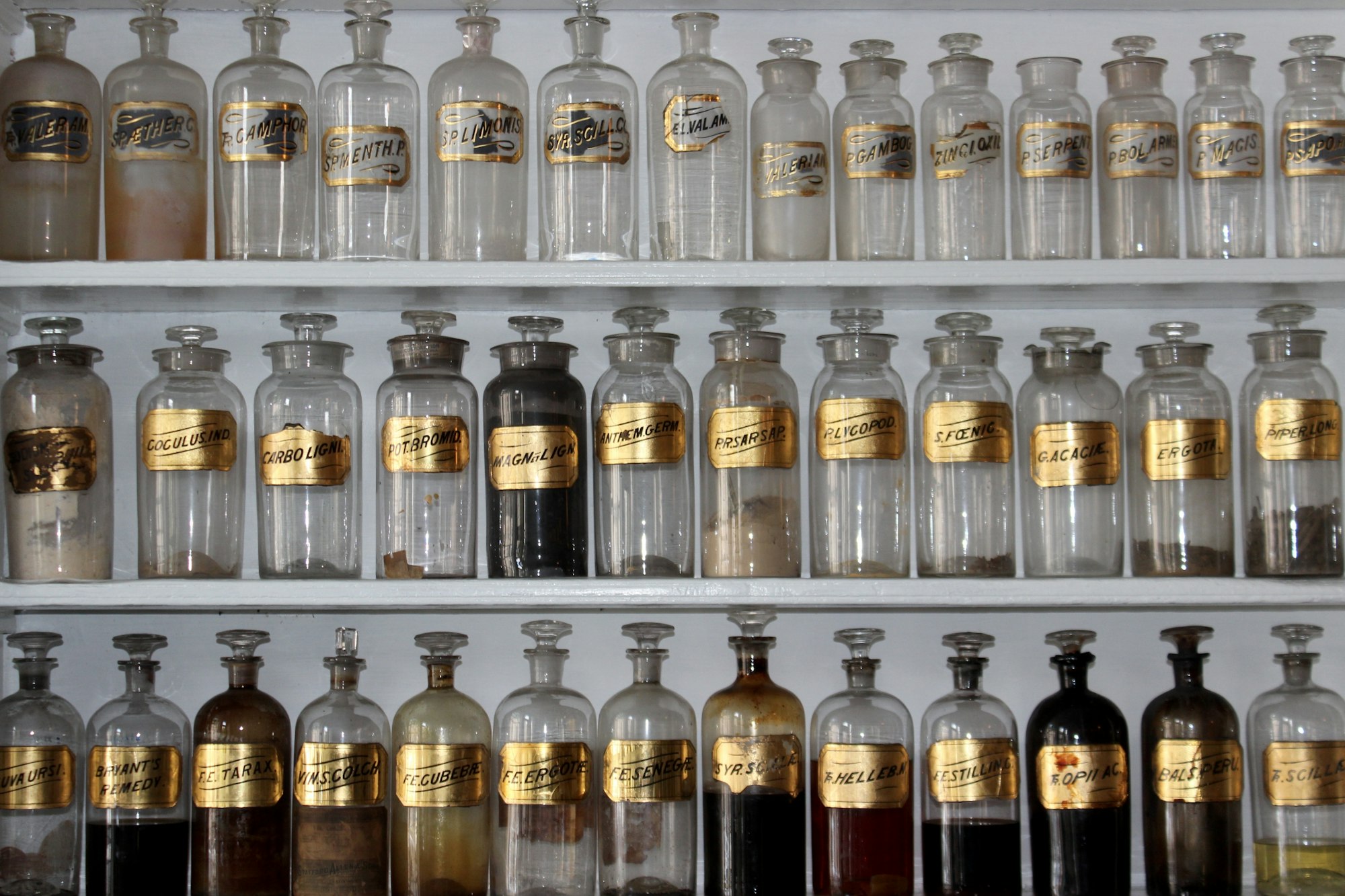 Étagère de flacons ambrés d'apothicaire — extraits en cours de purification en parfumerie — Noble Essence